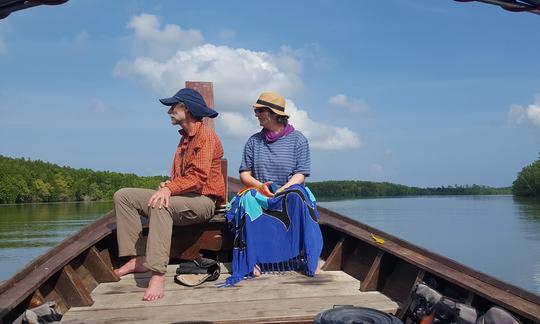 A couple sitting at the front of out traditional long-tail boat enjoying the views as we cruise though the Khao Lak mangroves