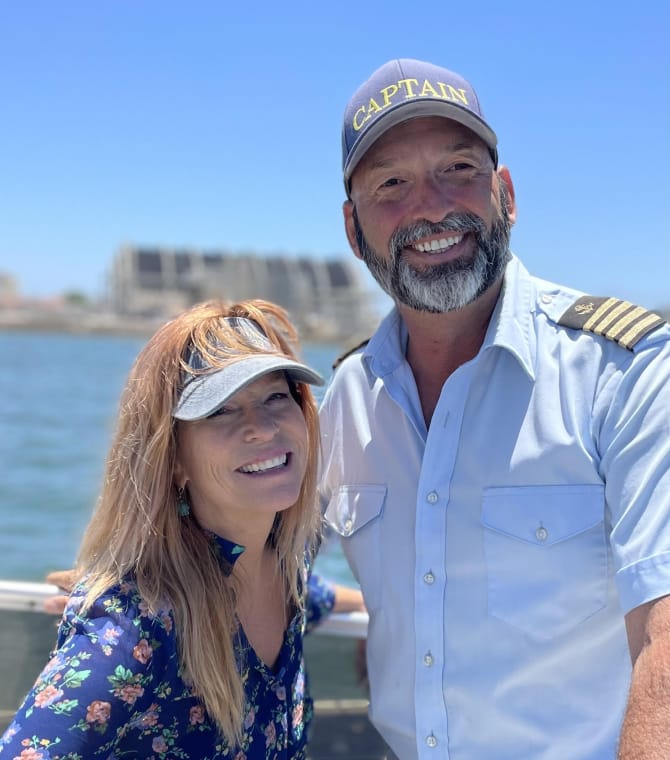A boat captain, smiling and posing with a guest.