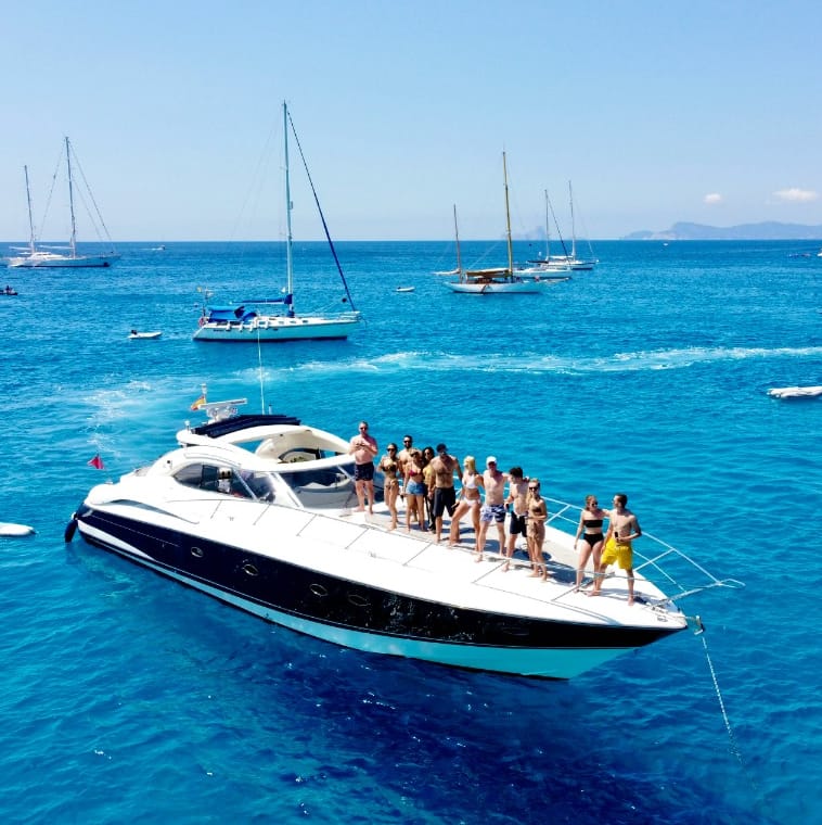 A group of people enjoying the sun, posing on the bow of a yacht.